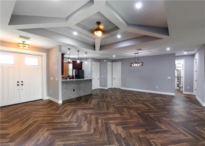 Living room with ceiling fan, dark parquet floors, and coffered ceiling