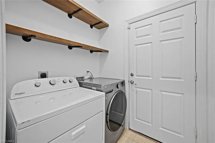 Laundry room with washer and clothes dryer and light tile patterned flooring
