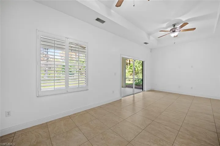 Unfurnished room with a raised ceiling, ceiling fan, and light tile patterned floors
