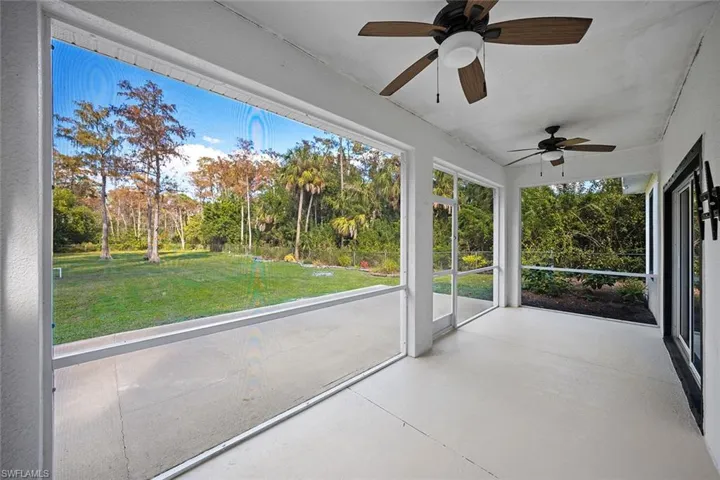 Unfurnished enclosed lanai/sunroom with a ceiling fan and view of scattered trees