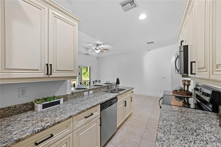 Kitchen granite counters, stainless steel appliances, light tile patterned flooring, a recessed lighting, and breakfast bar