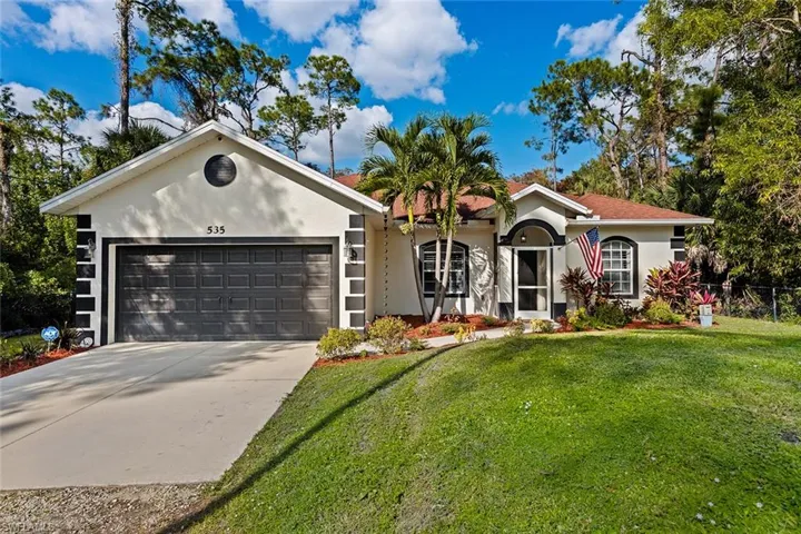 Ranch-style home featuring stucco siding, concrete driveway, a front yard, and a garage