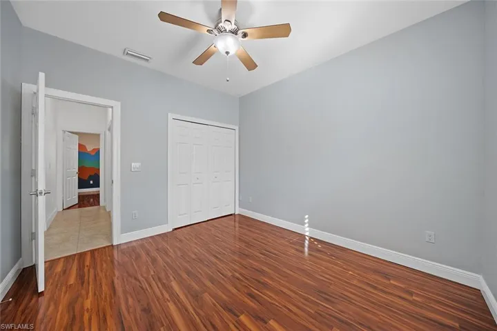 Unfurnished bedroom with wood finished floors, a ceiling fan, and a closet