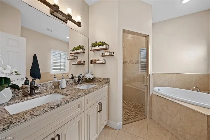 Bathroom featuring a shower stall, double vanity, a garden tub, recessed lighting, and light tile patterned flooring
