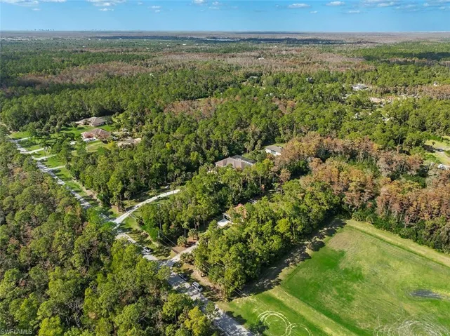 Aerial view of property and surrounding area featuring a forest