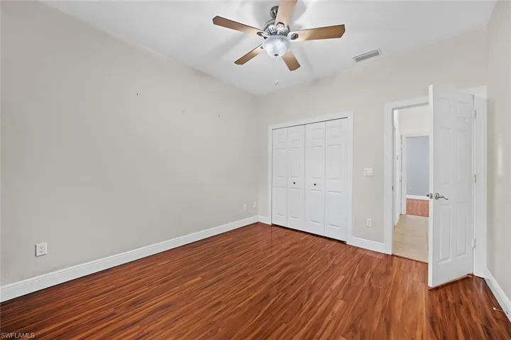 Unfurnished bedroom featuring dark wood-style floors, a ceiling fan, and a closet