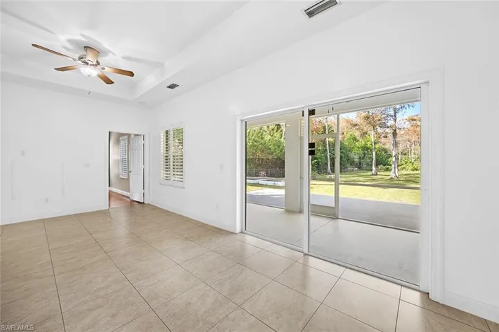 Empty room featuring a tray ceiling, a ceiling fan, and light tile patterned floors