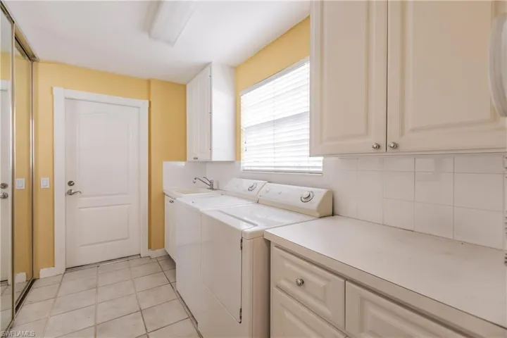 This laundry room has  a sink, plenty of cabinets, and a closet too!