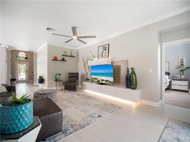 Living room featuring hardwood / wood-style flooring, ornamental molding, and ceiling fan