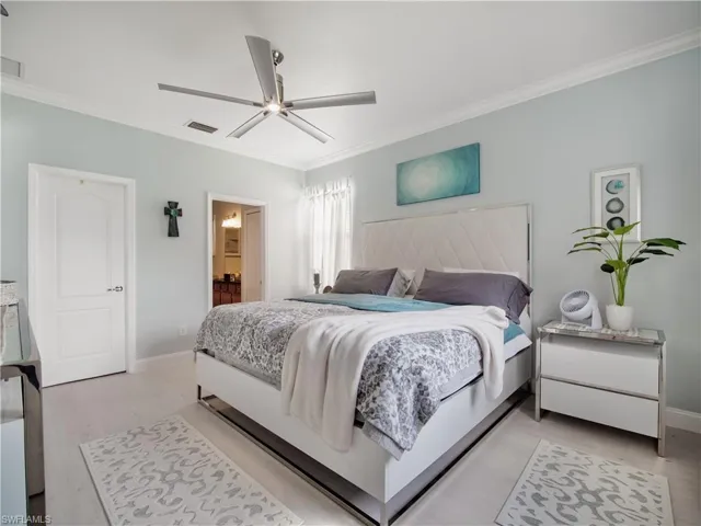 Bedroom with ornamental molding, light hardwood / wood-style flooring, connected bathroom, and ceiling fan