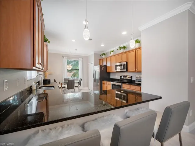 Kitchen with a kitchen bar, appliances with stainless steel finishes, sink, kitchen peninsula, and hanging light fixtures