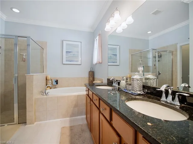 Bathroom with double vanity, crown molding, and separate shower and tub