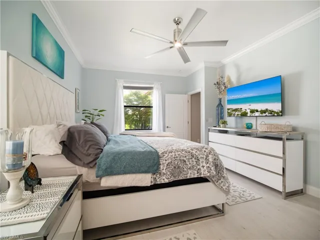 Bedroom featuring ornamental molding, light wood-type flooring, and ceiling fan