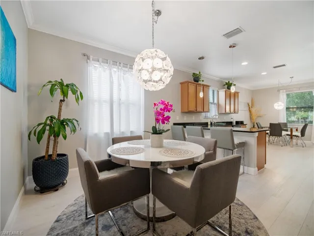 Dining room with an inviting chandelier, sink, crown molding, and light wood-type flooring