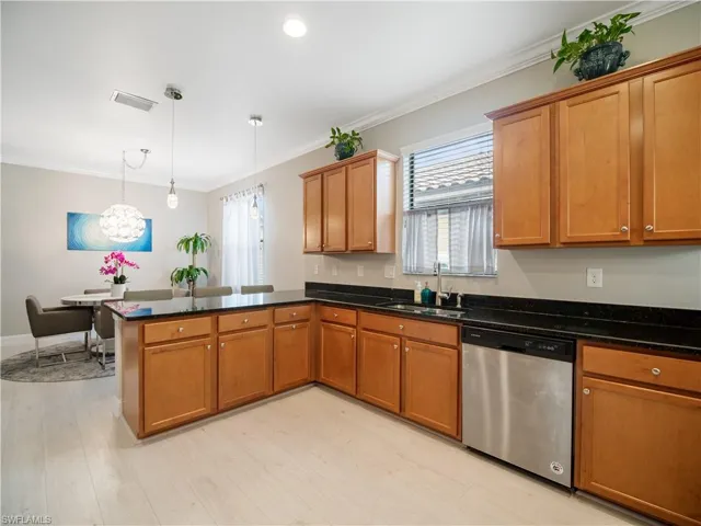 Kitchen featuring kitchen peninsula, stainless steel dishwasher, light hardwood / wood-style floors, pendant lighting, and sink