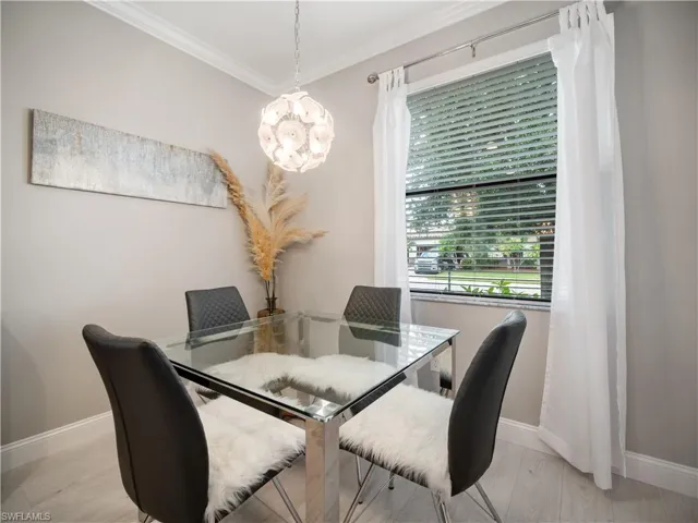 Dining area with ornamental molding, an inviting chandelier, and light wood-type flooring