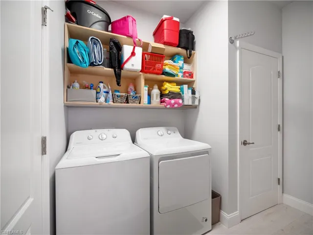 Laundry room with separate washer and dryer and light hardwood / wood-style floors