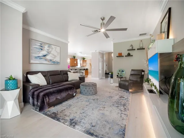 Living room featuring crown molding, light wood-type flooring, and ceiling fan