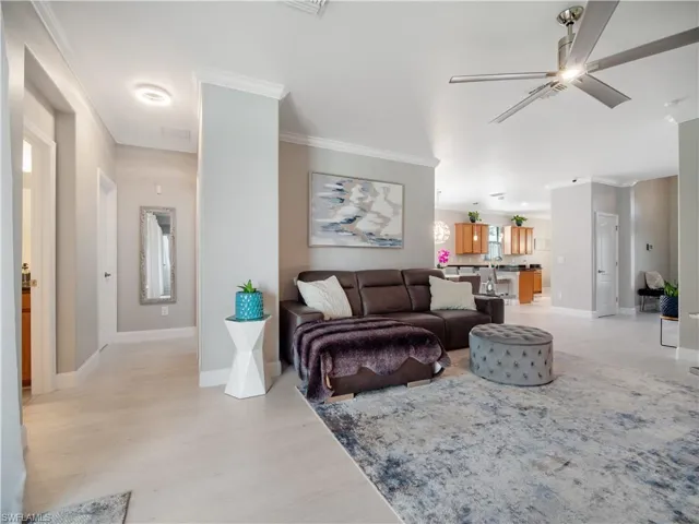 Living room with ornamental molding, light hardwood / wood-style flooring, and ceiling fan