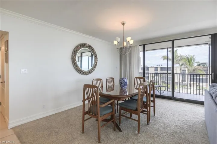 Dining area with ornamental molding, light carpet, and a chandelier