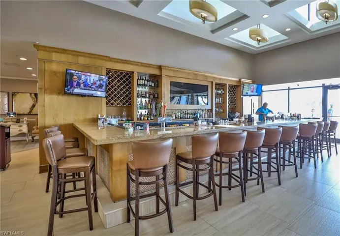 Bar with beamed ceiling, light stone counters, and coffered ceiling