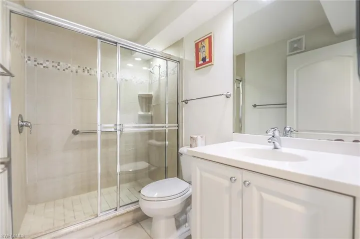 Bathroom with tile patterned floors, vanity, toilet, and walk in shower