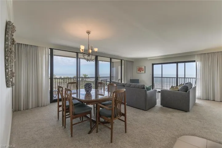 Carpeted dining area with a water view and a notable chandelier