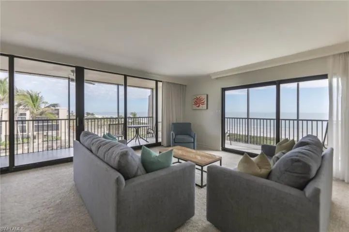 Living room with light carpet, crown molding, a water view, and a healthy amount of sunlight