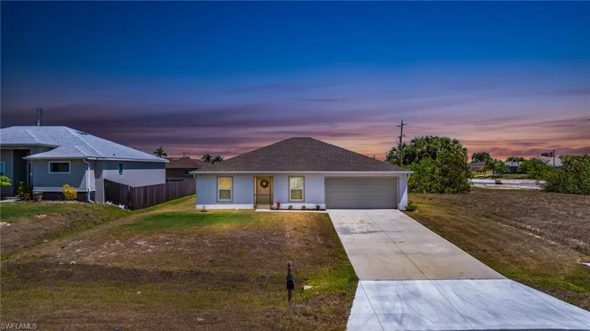 Ranch-style home featuring fence, driveway, a yard, and an attached garage