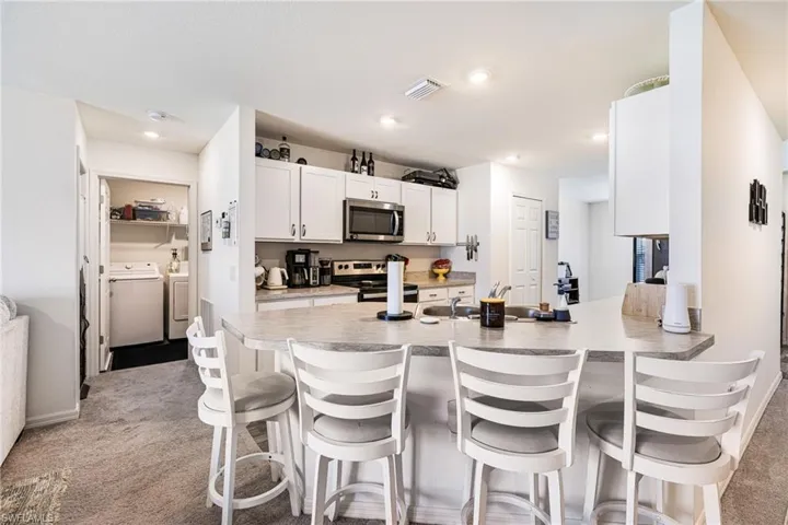 Kitchen featuring a breakfast bar area, visible vents, stainless steel appliances, and washer and clothes dryer
