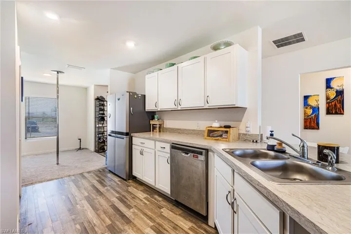Kitchen featuring light wood-style flooring, a sink, appliances with stainless steel finishes, visible vents, and light countertops