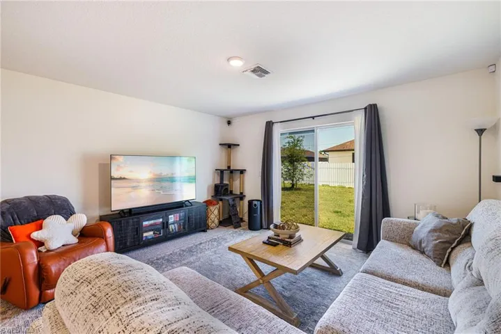 Living area featuring visible vents and carpet flooring