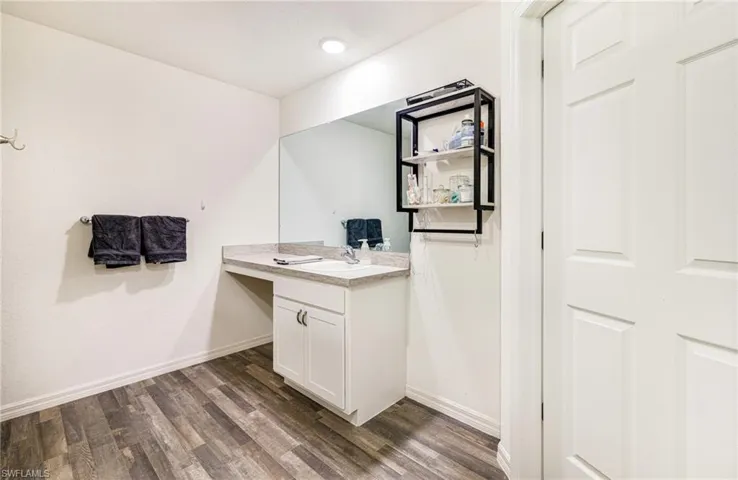 Bathroom with baseboards, wood finished floors, and vanity