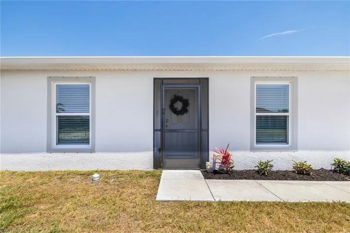 Entrance to property with a lawn and stucco siding