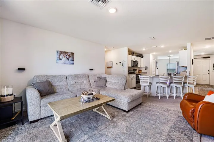 Carpeted living area with recessed lighting and visible vents