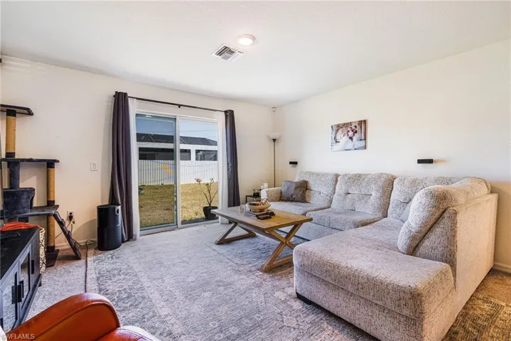 Carpeted living area featuring a wood stove and visible vents