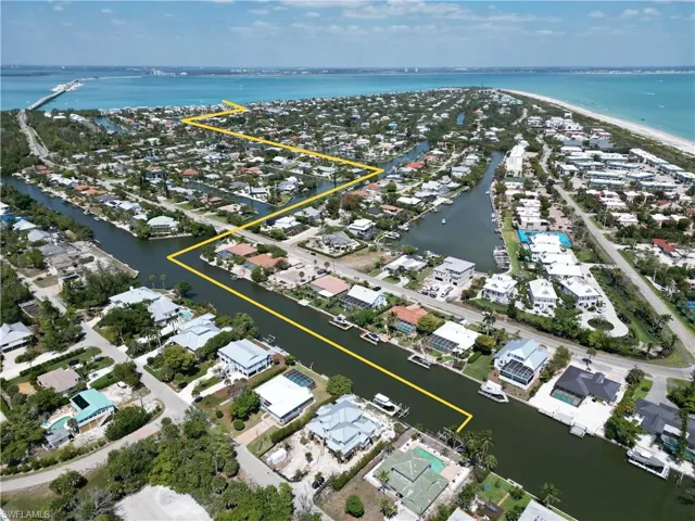 Aerial view showcasing a coastal community with numerous waterfront properties, canals, and proximity to a large body of water