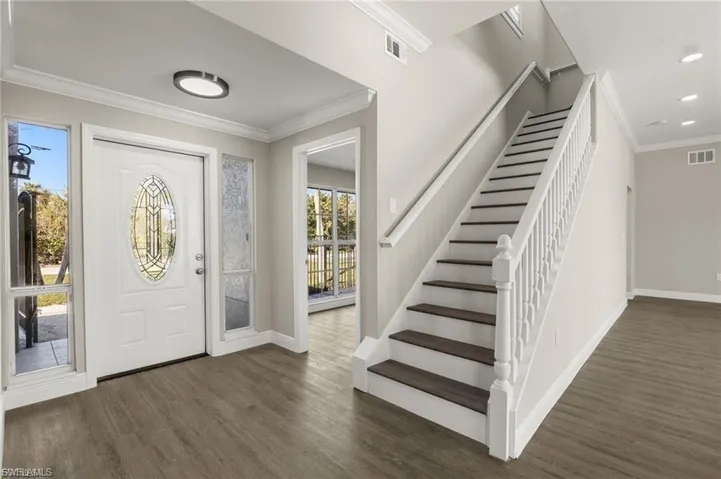 Foyer featuring a white entry door with an oval leaded glass insert, flanked by clear and textured glass sidelights