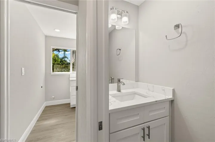 Bathroom vanity featuring a rectangular undermount sink, a white countertop with subtle veining, and a brushed nickel faucet