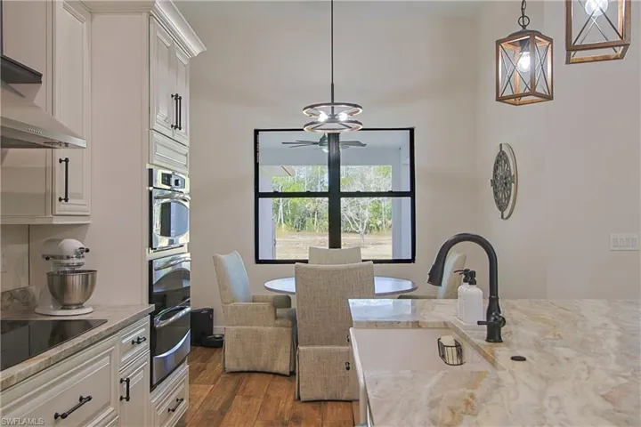 Kitchen featuring light stone countertops, pendant lighting, dark wood-type flooring, and black electric cooktop