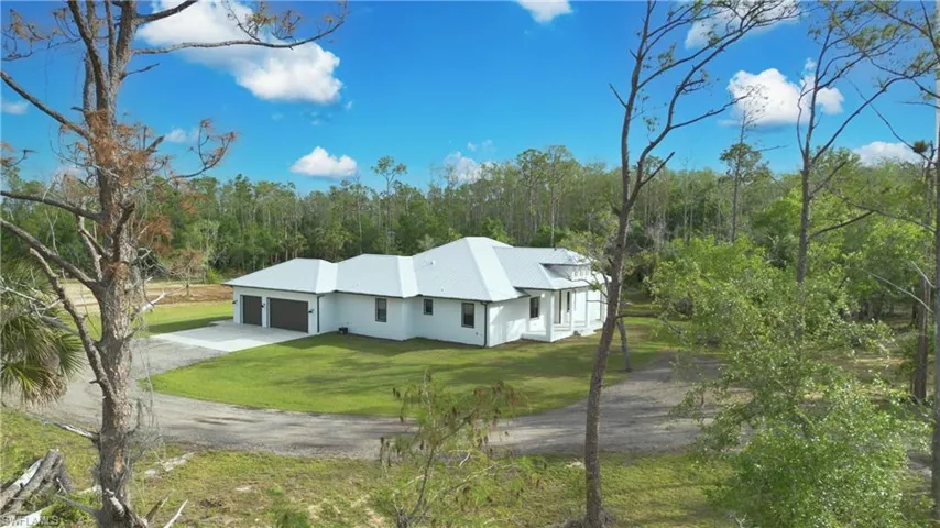 View of property exterior featuring dirt driveway, a yard, and a garage