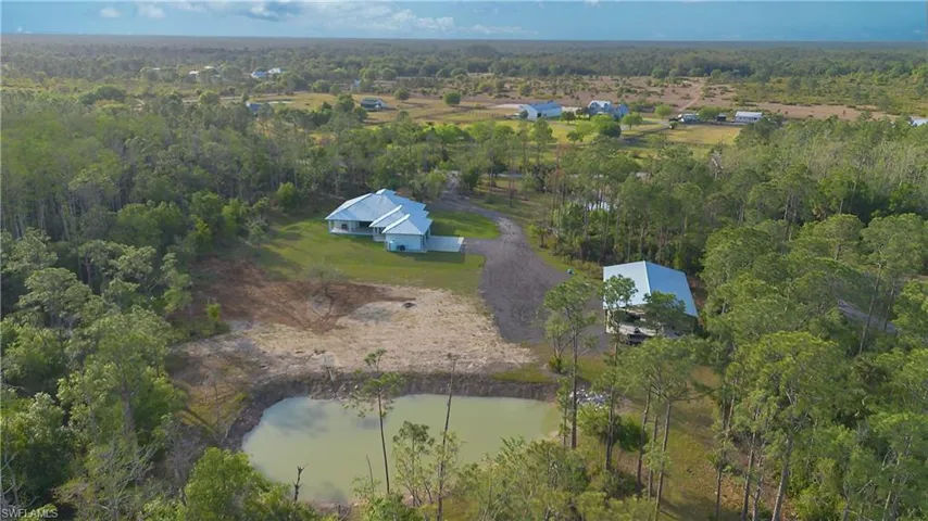 Aerial view of property and surrounding area featuring a nearby body of water and a forest