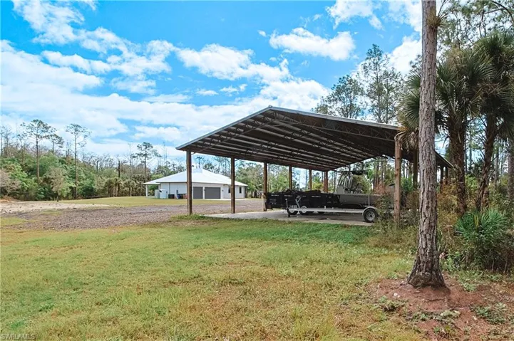 View of green lawn featuring a patio and a detached carport