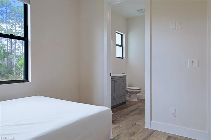 Bedroom with dark wood-type flooring and ensuite bathroom