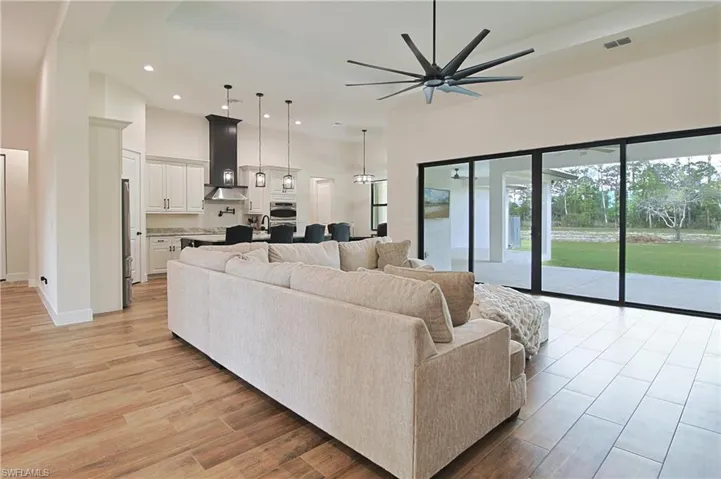 Living room with a high ceiling, light wood-type flooring, a ceiling fan, and recessed lighting