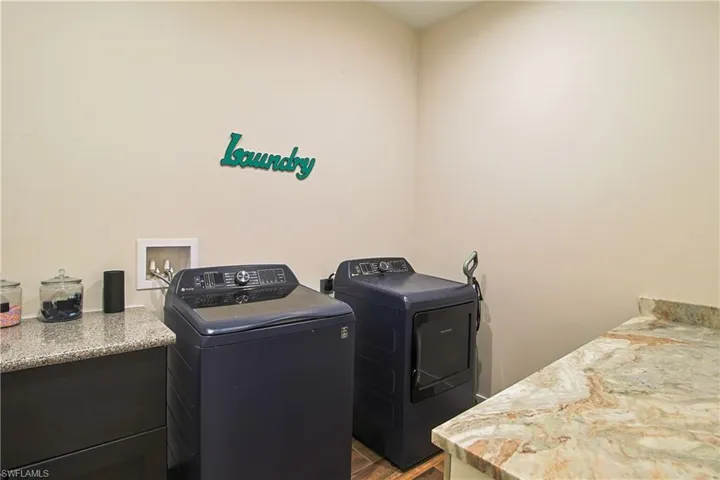 Laundry room with washer and clothes dryer, dark wood-style flooring, and cabinet space
