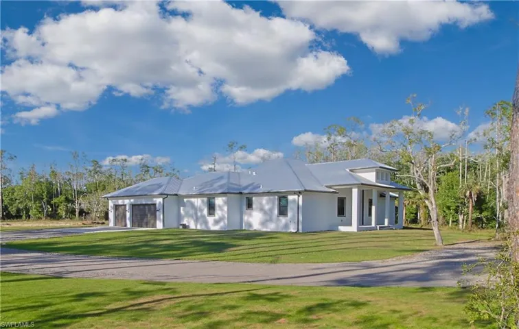 View of front of home featuring a front lawn, driveway, an attached garage, and stucco siding