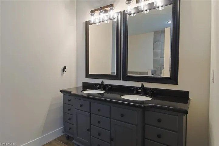 Bathroom featuring double vanity and dark wood-style floors