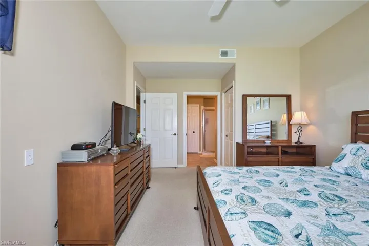 Bedroom with visible vents, a ceiling fan, and light colored carpet