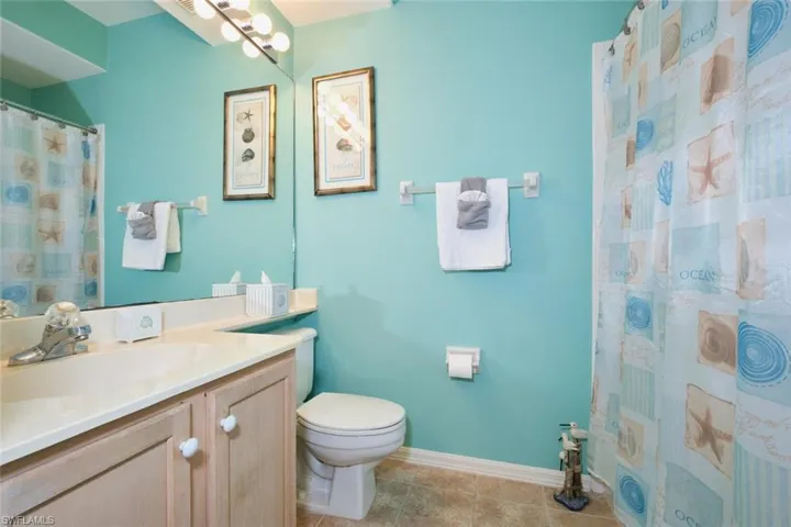 Bathroom featuring baseboards, toilet, vanity, a shower with curtain, and tile patterned flooring